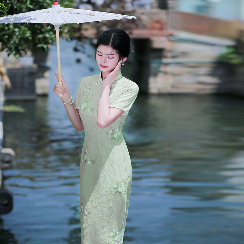 Woman wearing a pastel green modern Cheongsam dress with floral lace embroidery,