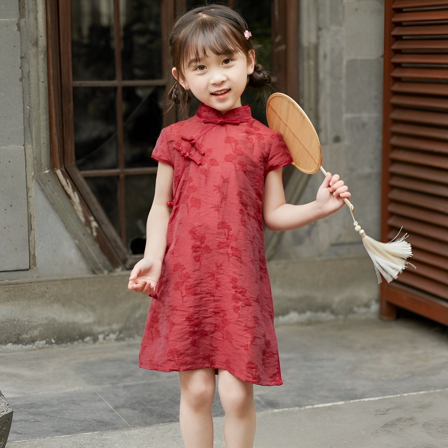 Girl wearing a red Chinese dress with floral print, available in 100-150cm.