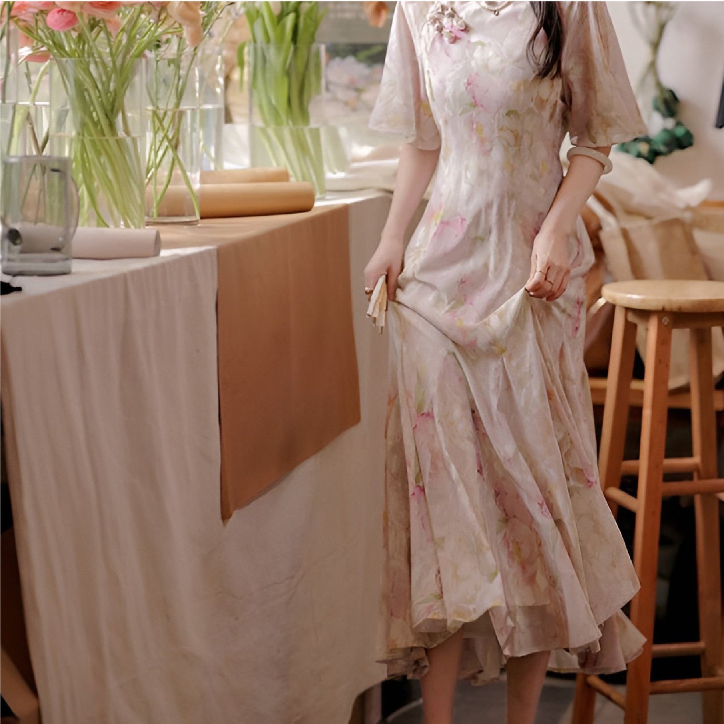 Woman wearing a luxurious modern cheongsam with delicate floral patterns, available in S, M, L.