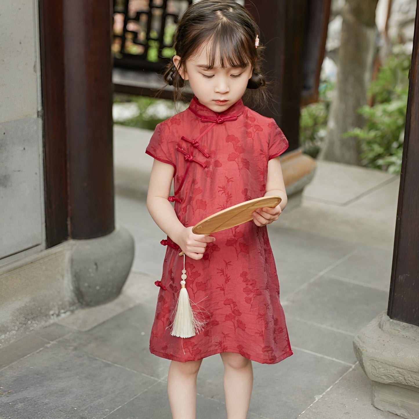 Girl wearing a red Chinese dress with floral print, available in 100-150cm.