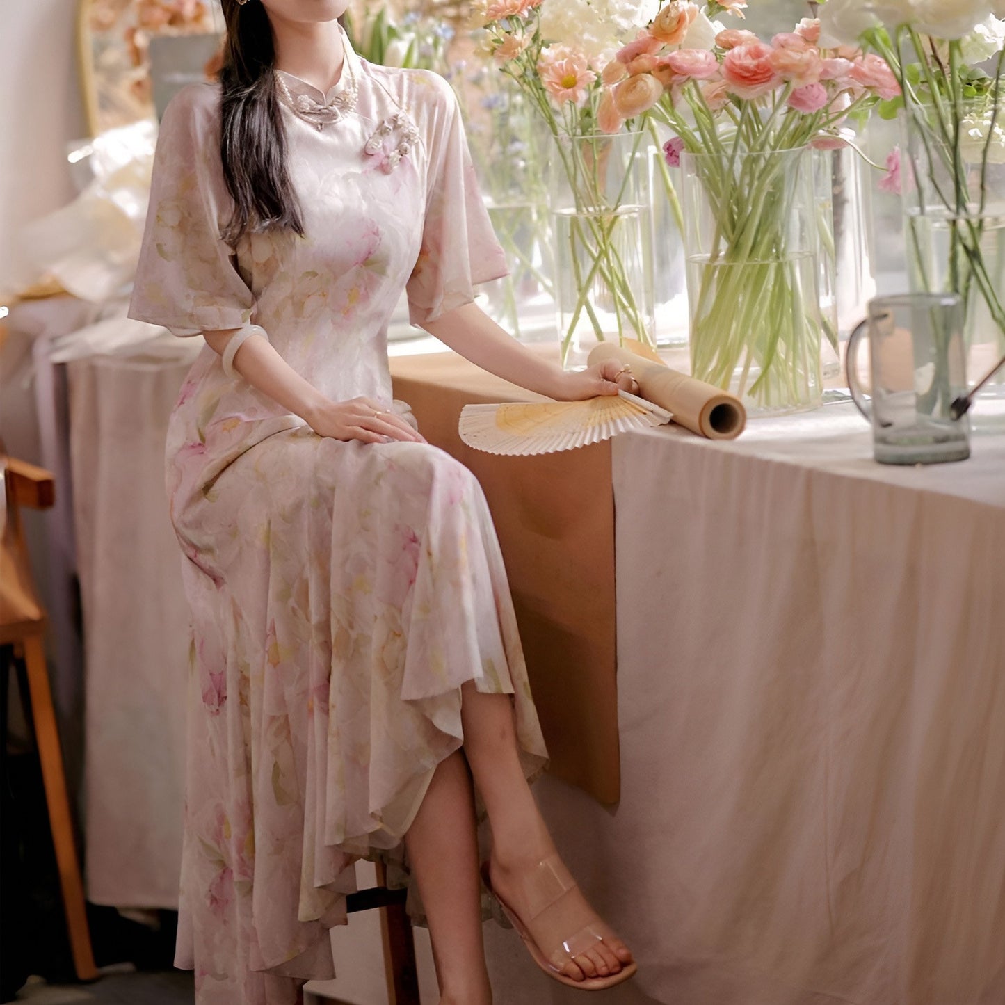 Woman wearing a luxurious modern cheongsam with delicate floral patterns, available in S, M, L.